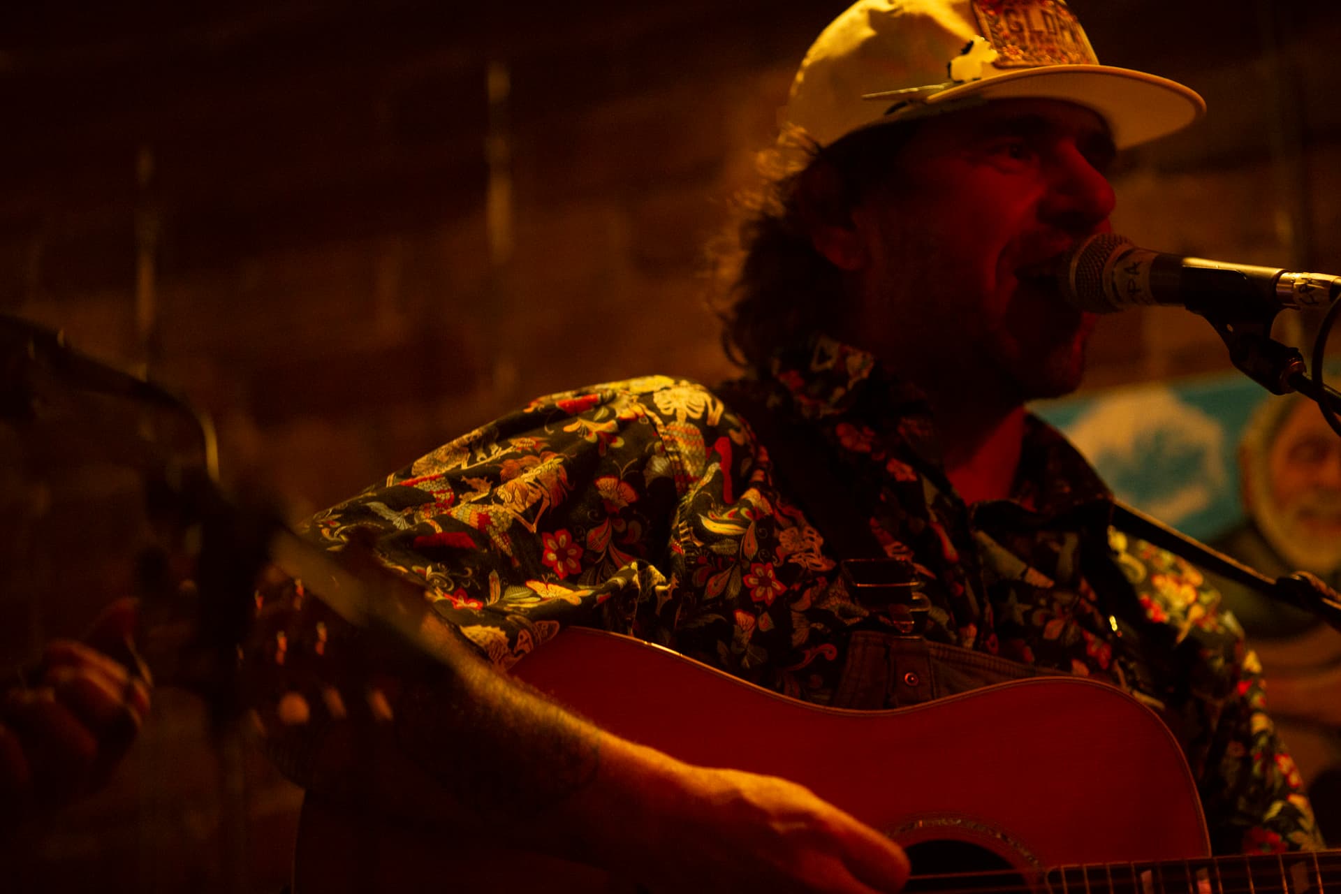 Ty Stonehawker singing into the mic, dramatic red stage light